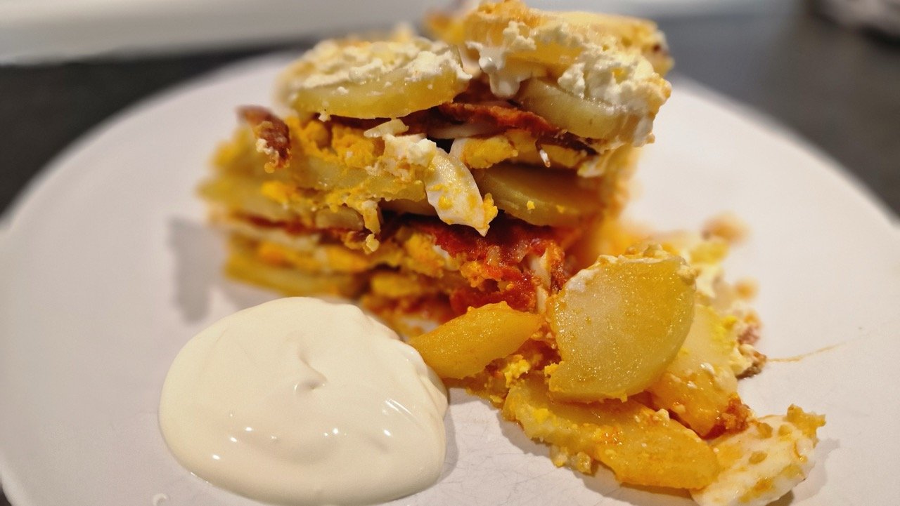einfacher ungarischer Kartoffelauflauf auf Teller mit saurer Sahne