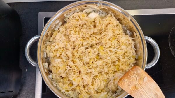 Sauerkraut, Wein, Wasser und Gewürze in den Topf geben