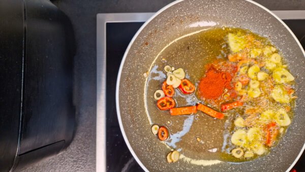 Paprikapulver wird in das Knoblauch-Chili-Öl eingerührt
