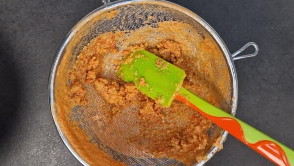 Fein pürierter Gazpacho wird durch ein Sieb passiert