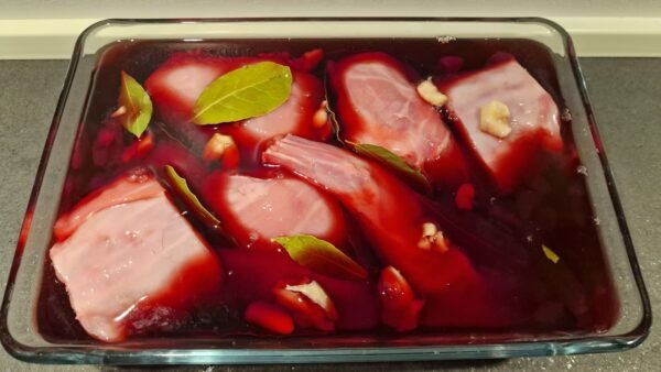 Kaninchenstücke mit Knoblauch und Lorbeer in Rotwein marinieren