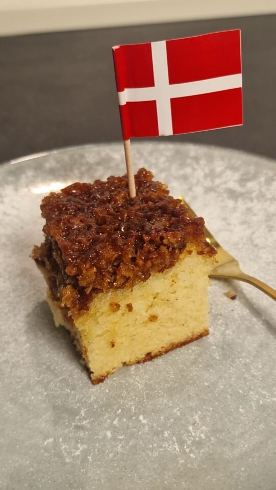 Stück Drømmekage fra Brovst mit einer kleinen dänischen Flagge