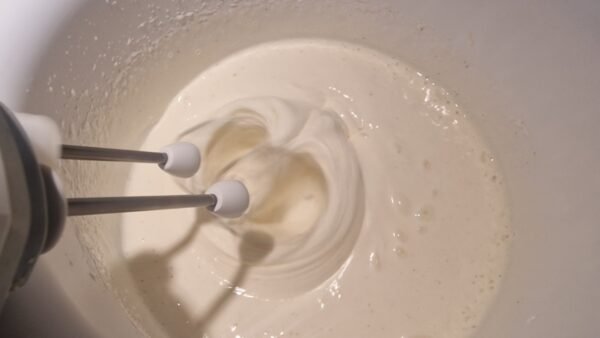 Eier und Zucker werden mit einem Handmixer hell und schaumig geschlagen