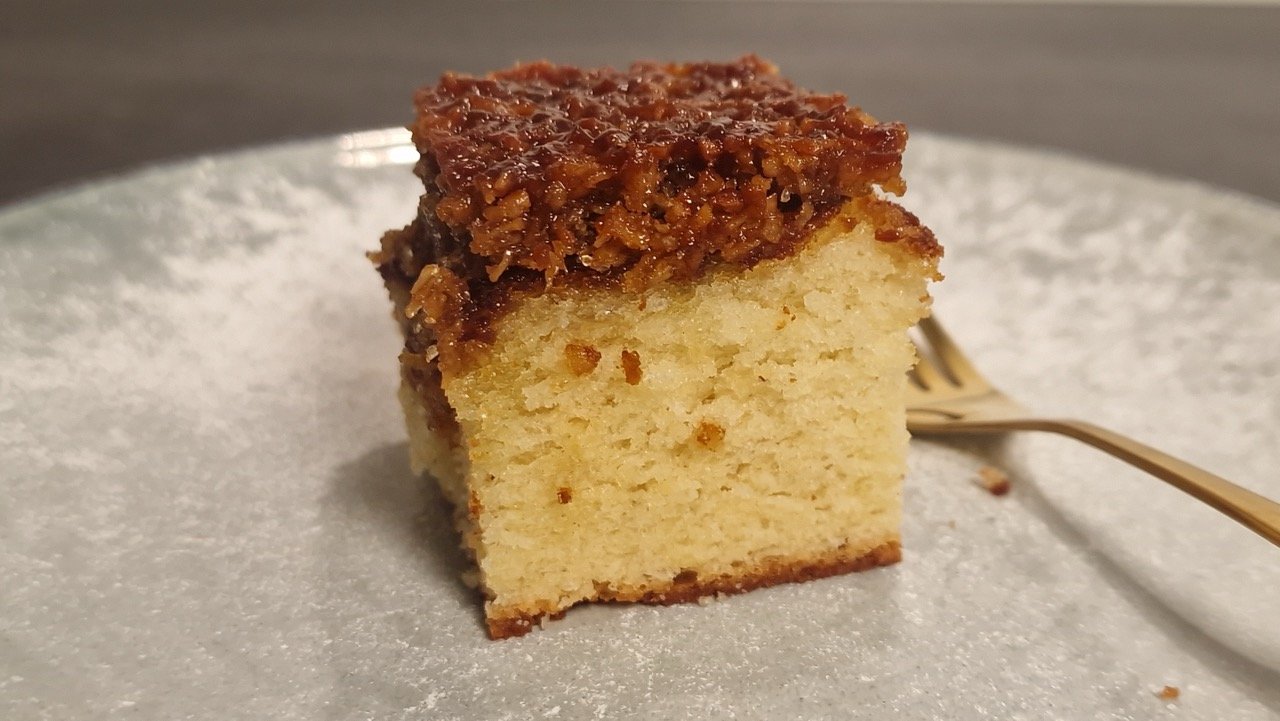 Stück dänischer Traumkuchen mit goldgelbem Biskuitboden und gebräuntem Kokosbelag