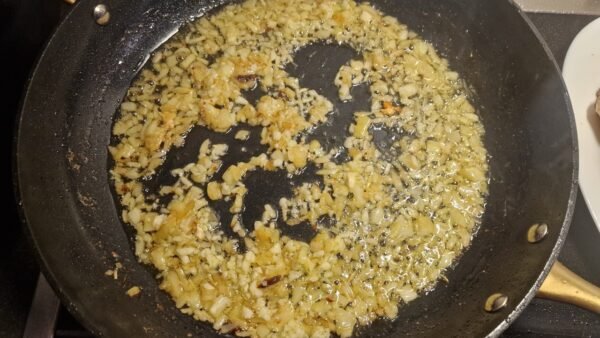 Zwiebel und Knoblauch beim Dünsten in der Pfanne