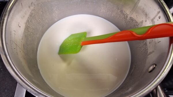 Heiße Milch wird zur Mehlschwitze gegeben
