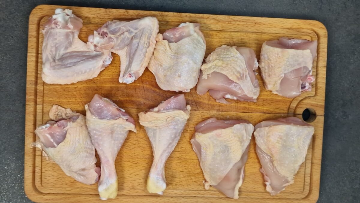 In zehn Stücke zerlegtes Hähnchen auf einem Schneidebrett