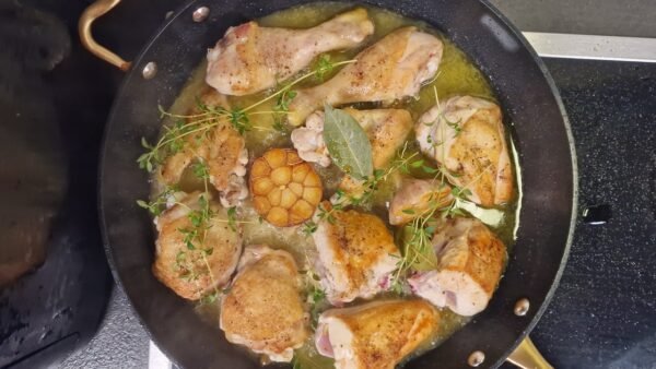 Hähnchen mit Knoblauch und Kräutern in einer Pfanne